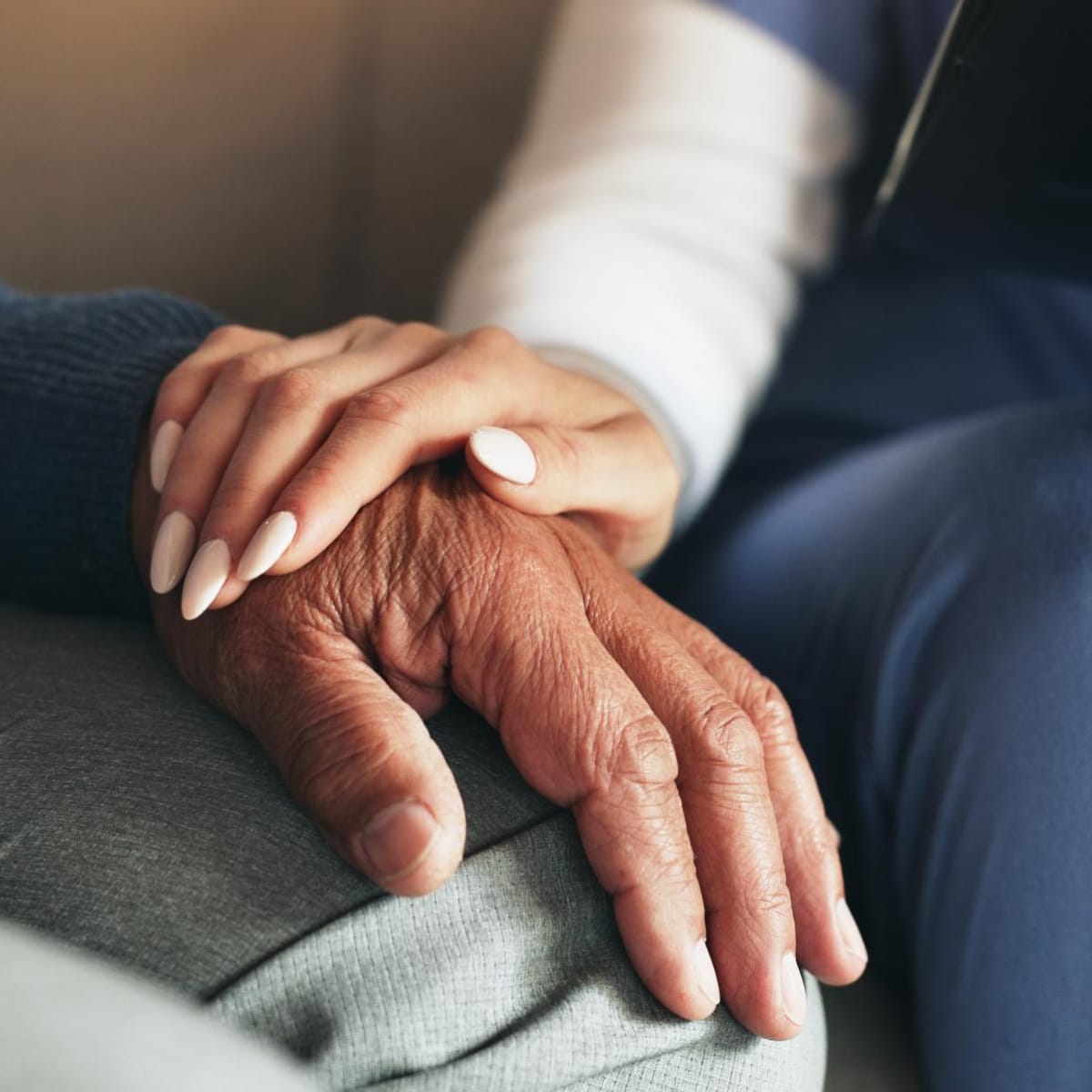 Close up of two hands on top of each other resting on someone